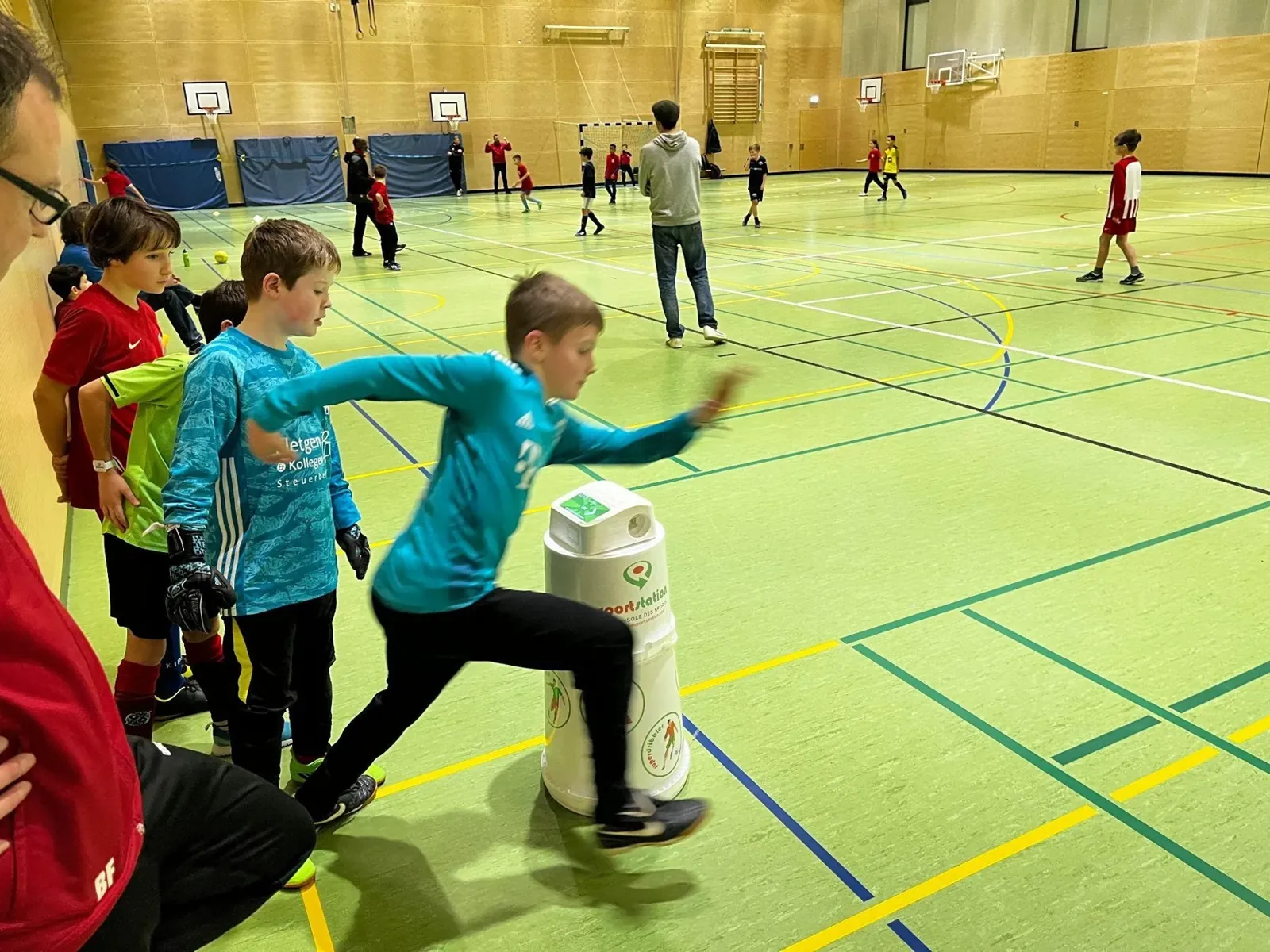 Kinder laufen an der sportstation2 in einer Turnhalle vorbei